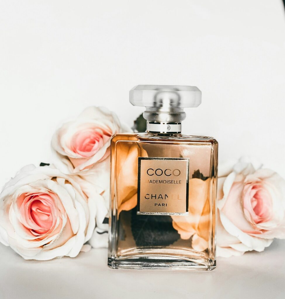 Artisanal clear glass perfume flacon with minimalist gold cap reflecting soft sunlight