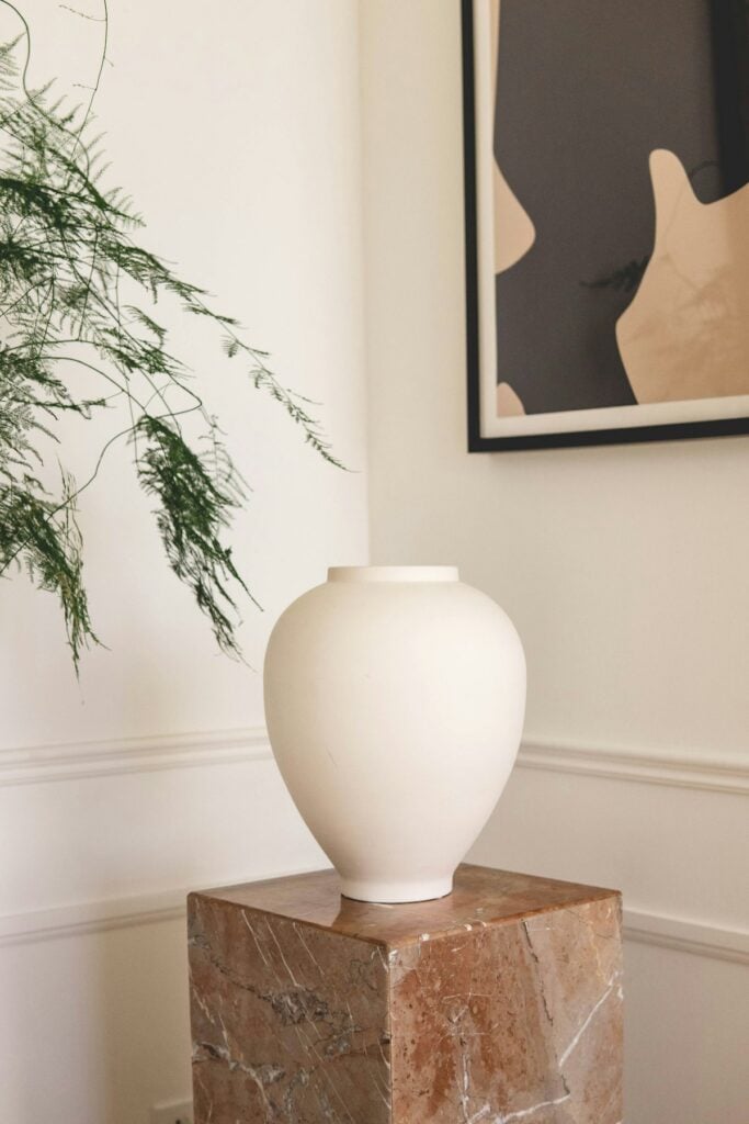Collection of hand-thrown stoneware bowls and vases on rustic travertine pedestal