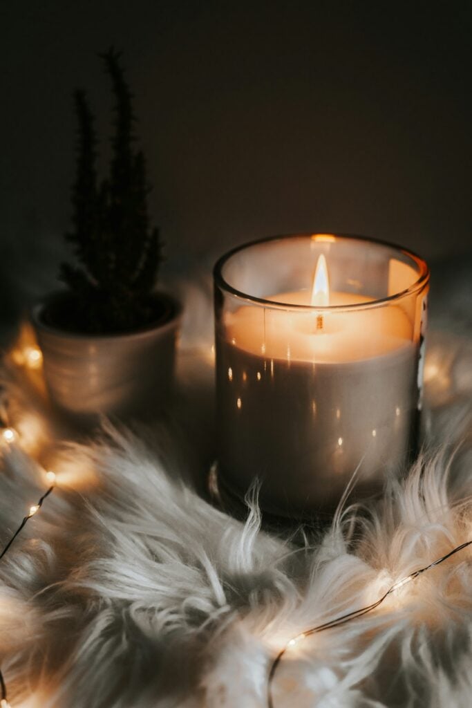 Pure amber beeswax taper candles burning softly in brass holders on dark wood table