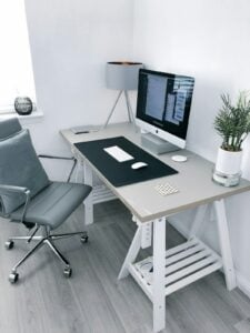 Minimalist walnut desk with aluminum laptop, ceramic mug, brass pen, and warm ambient lamp