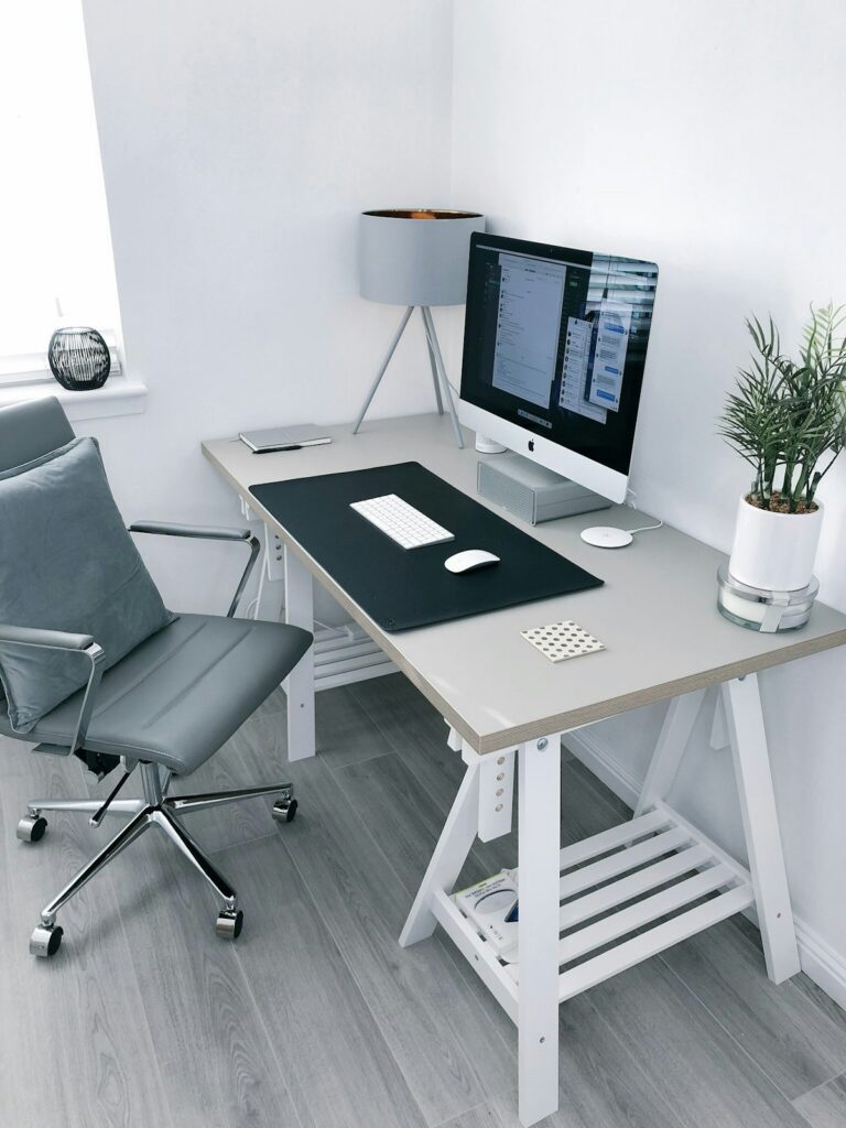 Minimalist walnut desk with aluminum laptop, ceramic mug, brass pen, and warm ambient lamp